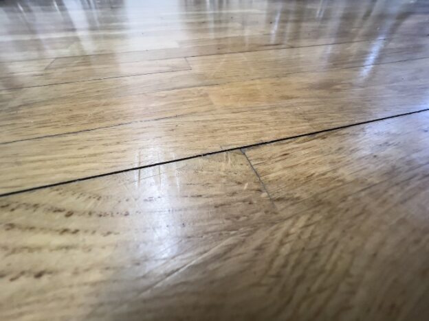 Light wood floor with a crack.