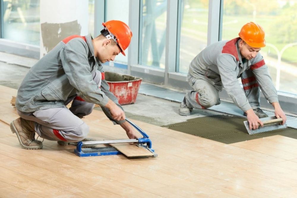 Two tilers installing floor tiles.