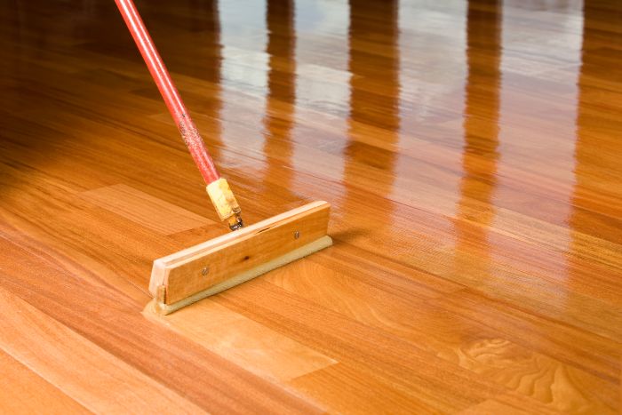 Applying wood floor finish with a squeegee.