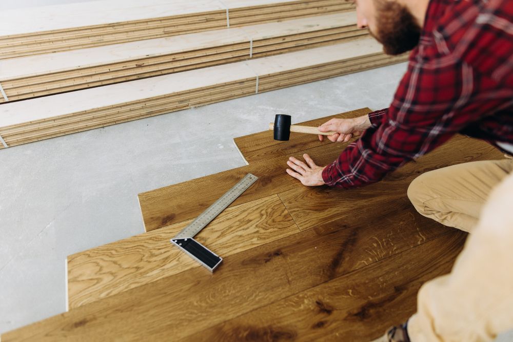 Man installing wood flooring with mallet.