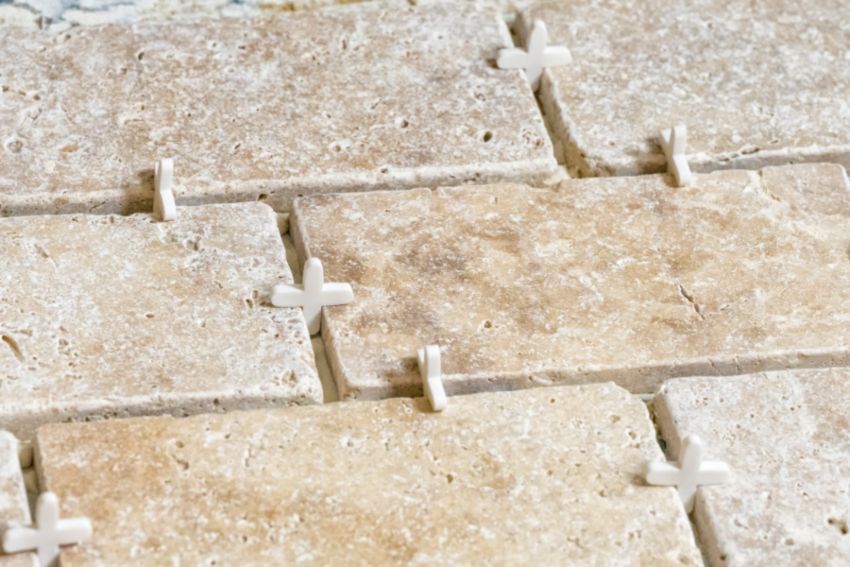 Beige travertine tiles with spacers.