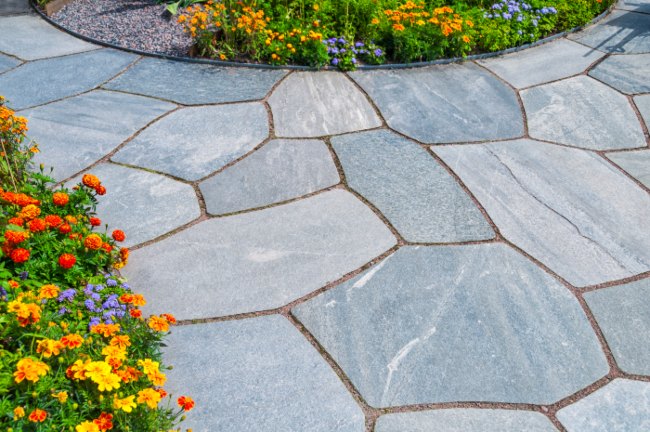 Stone path bordered by colorful flowers.