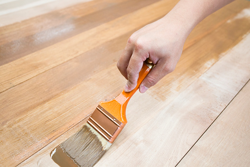 Hand staining wooden floorboards.