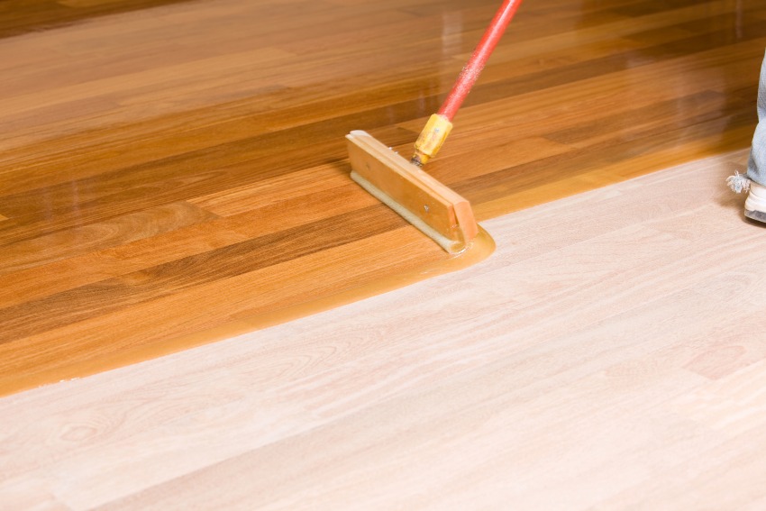 An individual using a brush illustrating refinishing & resurfacing wood floors in MD, DC, & VA Area.