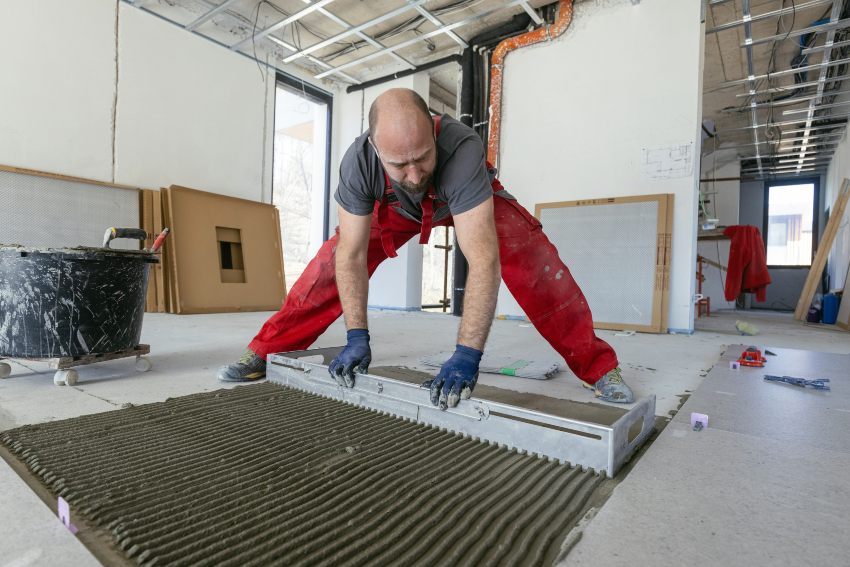 A floor installer spreading thin set adhesive on subfloor in Baltimore & D.C Metropolitan Areas