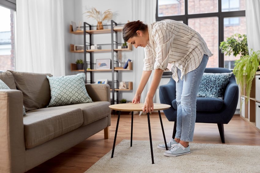 A person placing a table on a clean wood floor, illustrating How To Protect Floors from Furniture